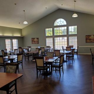An elegant dining area with arranged tables and chairs, featuring large windows for natural lighting.