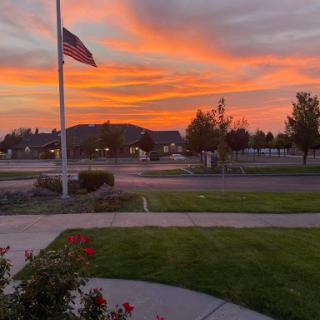 A beautiful sunset painted the sky with vibrant colors, framed by an American flag and serene landscape.