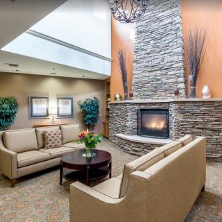 A cozy lounge features comfortable seating and a warm fireplace set against a stone wall, creating an inviting ambiance.