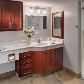 A well-lit bathroom with a wooden vanity and mirror, featuring dual sinks and decorative flowers.