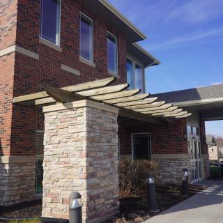 A modern brick building with a stone column and canopy at the entrance.
