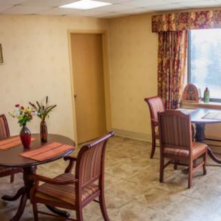 A cozy dining area with tables and chairs, decorated with vases of flowers near a window.