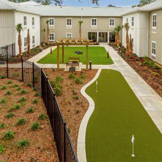 A courtyard featuring a landscaped garden with artificial turf and pathways, surrounded by residential buildings.