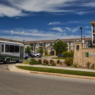 A residential complex with a bus parked nearby under a blue sky with clouds.
