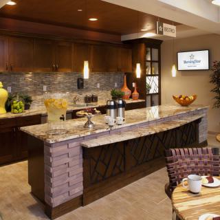 A modern kitchen with a large countertop, stylish lighting, and dining area.