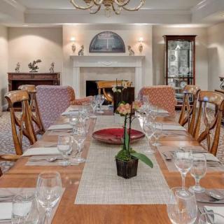 An elegantly set dining room table with a fireplace in the background.