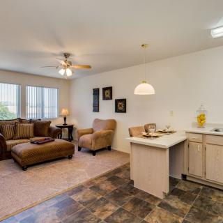 A cozy living room with a sofa, armchair, and coffee table, featuring an open floor plan with adjacent kitchen area.
