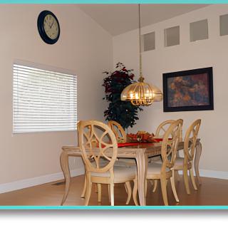 A cozy dining room with a wooden table and six chairs under a hanging chandelier.
