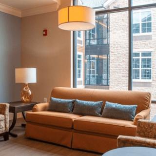 A cozy living room with a brown sofa, blue cushions, and warm lighting.