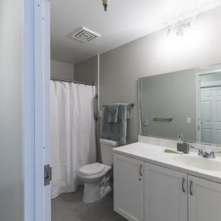 A modern bathroom with a large mirror, a white sink, and a shower area with a curtain.