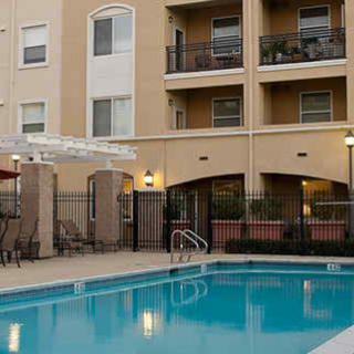 An outdoor view of an apartment complex featuring a swimming pool with balconies above.