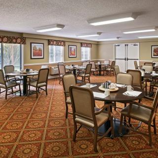 A neatly arranged dining room with tables and chairs on a patterned carpet.