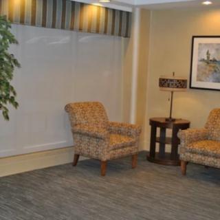 A cozy corner with two upholstered chairs, a small table with a lamp, and wall artwork.