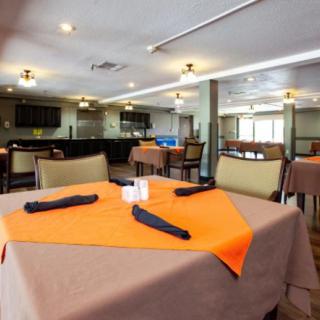 A modern restaurant dining area with neatly set tables and an orange tablecloth.