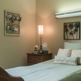 A cozy bedroom with a neatly made bed, nightstand, and wall art.