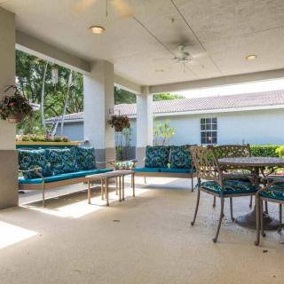A cozy covered patio with seating and greenery.
