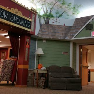 A cozy interior space resembling a theater lobby with a 'Now Showing' sign and comfortable seating.