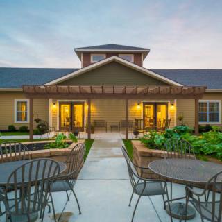 A picturesque patio area with outdoor seating in front of a residential building during the evening.