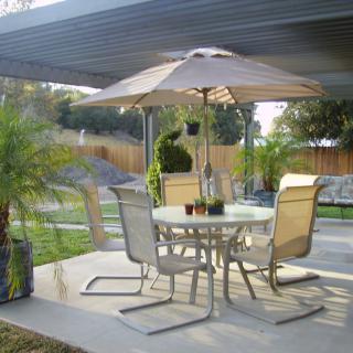 A cozy patio setup with chairs, a table, and an umbrella in a backyard setting.