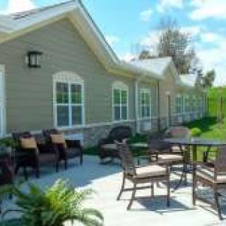 A sunny outdoor patio area with chairs and tables in front of a building.