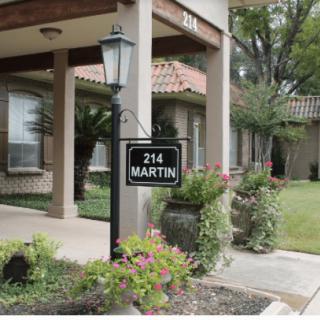 A building with a landscaped garden and a sign displaying the address '214 Martin' next to a lamp post.