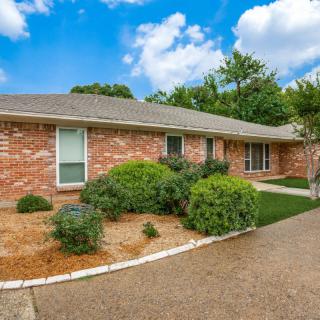 A single-story brick house with neatly maintained landscaping and a driveway.