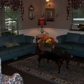 A cozy living room with two sofas, a coffee table adorned with flowers, and ambient lighting.