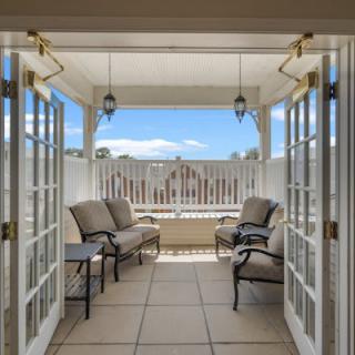 A cozy balcony with comfortable seating and a scenic view through French doors.