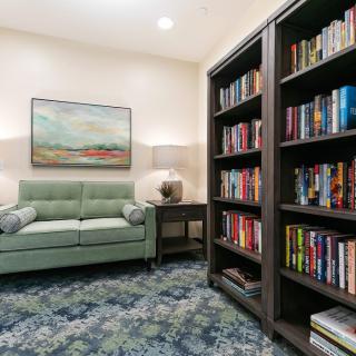 A cozy reading room with bookshelves, a comfortable sofa, and a decorative painting.