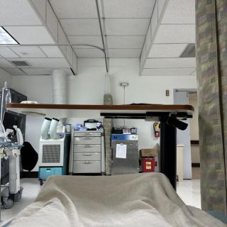 View from a hospital bed showcasing medical equipment and a curtain partition.