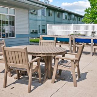 An outdoor patio area with a wooden table and chairs next to a building on a sunny day.