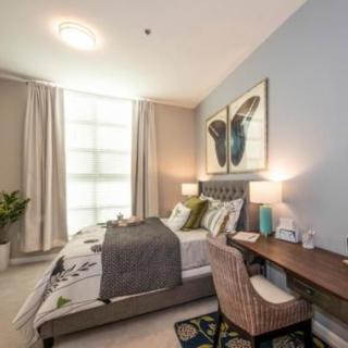 A modern bedroom with stylish decor, featuring a bed, desk, and wall art.