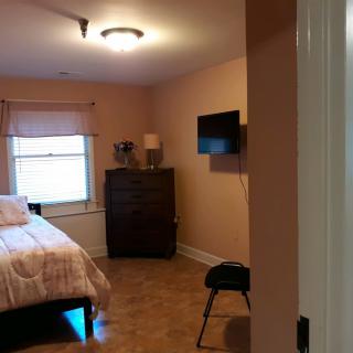 A cozy bedroom with a bed, dresser, and wall-mounted TV.