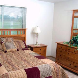 A cozy bedroom with a wooden bed, dresser, and patterned bedding.