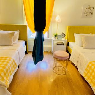 A cozy bedroom featuring twin beds with yellow accents and bright decor.