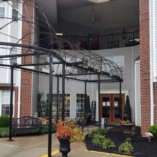 The entrance of a building with decorative landscaping and metal framework.