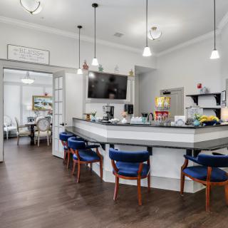 A modern kitchen with a central counter, blue chairs, and pendant lighting.