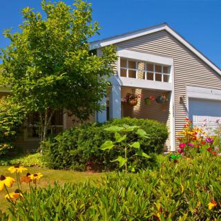 A charming house with a beautifully landscaped front yard featuring lush greenery and vibrant flowers.
