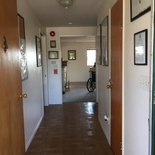 A hallway with wooden floors, several doors, and a bicycle at the end.