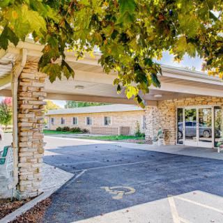 A welcoming entrance with a stone facade and canopy, surrounded by greenery.