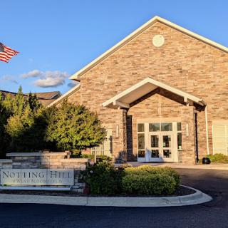 A welcoming view of a brick building with a flag, bathed in warm sunlight.