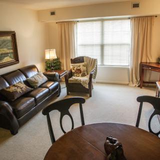 A cozy living room featuring a comfortable sofa, a wooden table, and natural light streaming through the window.