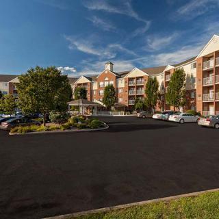 A modern apartment complex with a spacious parking lot and surrounding greenery.