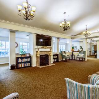A spacious and elegantly designed living room with chandeliers, a fireplace, bookshelves, and comfortable seating.