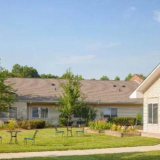 A sunny day view of a residential building with a neatly maintained lawn and scattered benches.