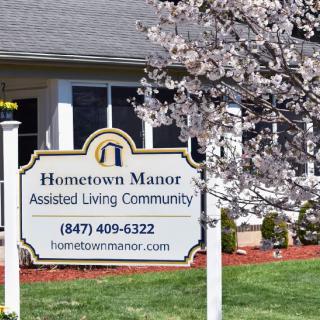 Sign for Hometown Manor Assisted Living Community with cherry blossoms in the foreground.