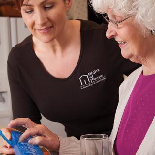 A caregiver assisting an elderly woman with using a tablet.