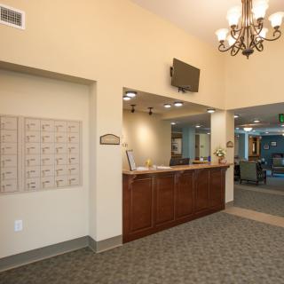 A well-lit reception area featuring a wooden desk and a chandelier.