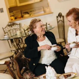 Two elderly women enjoying tea and conversation in a cozy living room.
