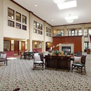 A spacious and modern lobby featuring comfortable seating, a central fireplace, and ample natural lighting.